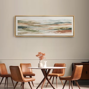 May include: An abstract landscape painting in a gold frame. The artwork features a blend of earthy tones, including greens, browns, and beige, creating a serene and naturalistic scene. The painting hangs above a dining table with brown leather chairs.
