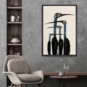 May include: Abstract art print featuring a minimalist design of four stylized birds in black and blue against a cream background. The birds have long beaks and yellow eyes, framed in a black wooden frame. The artwork is displayed in a modern interior setting.