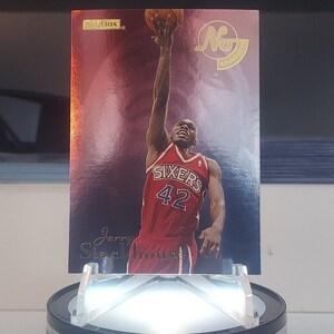 May include: A red, white, and blue basketball card featuring Jerry Stackhouse in a red Philadelphia Sixers jersey with the number 42. The card has a gold background with the words "SkyBox" and "No. 1 Rookie" printed on it.