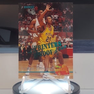 May include: A basketball trading card featuring a green and white "PRINTERS" logo with a yellow and black basketball player wearing a yellow jersey with the number 25 and the word "MICHIGAN" on it. The card is from the "ALL ROOKIES" series.