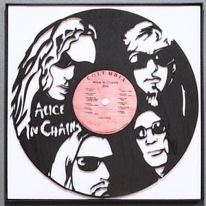 May include: Black and white cut-out art piece featuring the band Alice in Chains. The design incorporates the band members' faces around a red Columbia record label. The album title "Dirt" is visible.