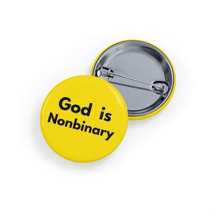 Puede incluir: Dos insignias redondas amarillas. Una insignia muestra el texto "God is Nonbinary" en negro. La otra insignia es plateada con un alfiler de seguridad en la parte posterior. Las insignias están sobre un fondo blanco.