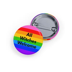 Puede incluir: Dos insignias redondas. Una muestra un degradado arcoíris con el texto "All Witches Welcome" en negro. La otra muestra la parte trasera plateada del alfiler. Insignias para ropa o bolsos.