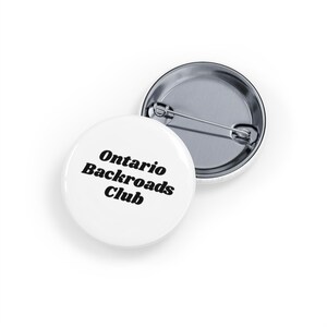 Peut inclure: Un badge rond blanc avec le texte noir Ontario Backroads Club imprimé sur le devant. Le dos du badge est en métal argenté et comprend un mécanisme d'épingle standard pour le fixer sur des vêtements ou des accessoires en tissu.
