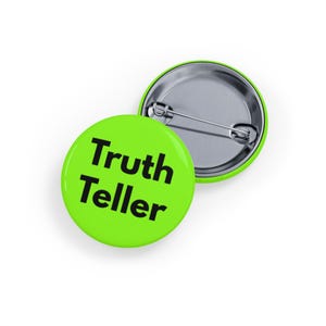 May include: Two round, lime green pinback buttons. One button displays the text "Truth Teller" in black, bold font. The other button is silver with a safety pin back. The buttons are on a white background.