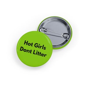 May include: Two round, lime green buttons with the text "Hot Girls Dont Litter" in black. One button is face up, and the other is face down, revealing a silver pin back.
