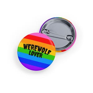 Puede incluir: Dos insignias redondas. Una insignia presenta un diseño de arcoíris con el texto "WEREWOLF LOVER" en negro. La otra insignia tiene un borde de arcoíris y un respaldo de alfiler plateado. Las insignias están sobre un fondo blanco.