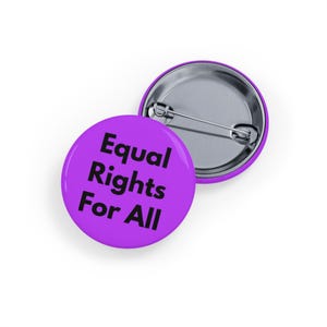 May include: Two round, purple buttons with the text "Equal Rights For All" in black. One button is face up, and the other is face down, showing the pin back. The buttons are on a white background.