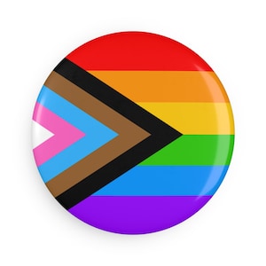 May include: A round button with a glossy finish, featuring a rainbow design with a black chevron and additional colors. The button's design incorporates the colors of the Pride flag and the Progress Pride flag.