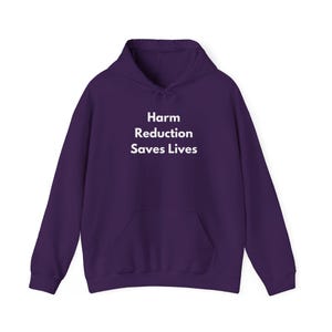May include: A dark purple hoodie with a drawstring hood and a front pocket. The text "Harm Reduction Saves Lives" is printed in white across the chest. The hoodie is made of a soft material.