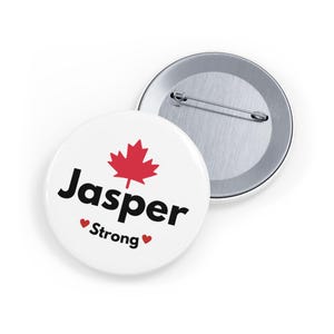 May include: White button with a red maple leaf and the text "Jasper Strong" in black with red hearts on either side of the word "Strong".