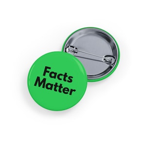 Può includere: Una spilla rotonda con una superficie verde brillante e il testo nero "Facts Matter" stampato sul davanti. Il retro della spilla è in argento metallizzato e presenta un meccanismo a spilla orizzontale in metallo per il fissaggio ai tessuti.