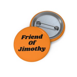 Op de afbeelding: Een ronde oranje button met de zwarte tekst Friend Of Jimothy op de voorzijde. De achterkant van de button is van zilverkleurig metaal en bevat een horizontale speld voor bevestiging aan kleding of stoffen accessoires.