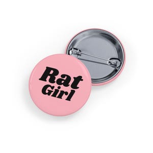 May include: Pink button with the text "Rat Girl" in black retro font.