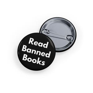 Może przedstawiać: Czarny guzik z białym tekstem, który brzmi "Read Banned Books".