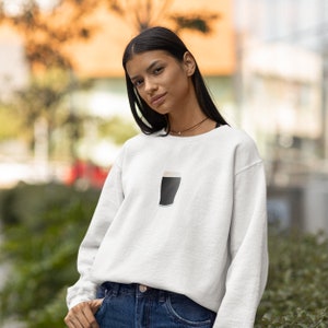 May include: White sweatshirt featuring a graphic of a pint of stout. The design is a simple illustration of a dark beer with a creamy head. The sweatshirt is a casual, everyday garment, suitable for various occasions.