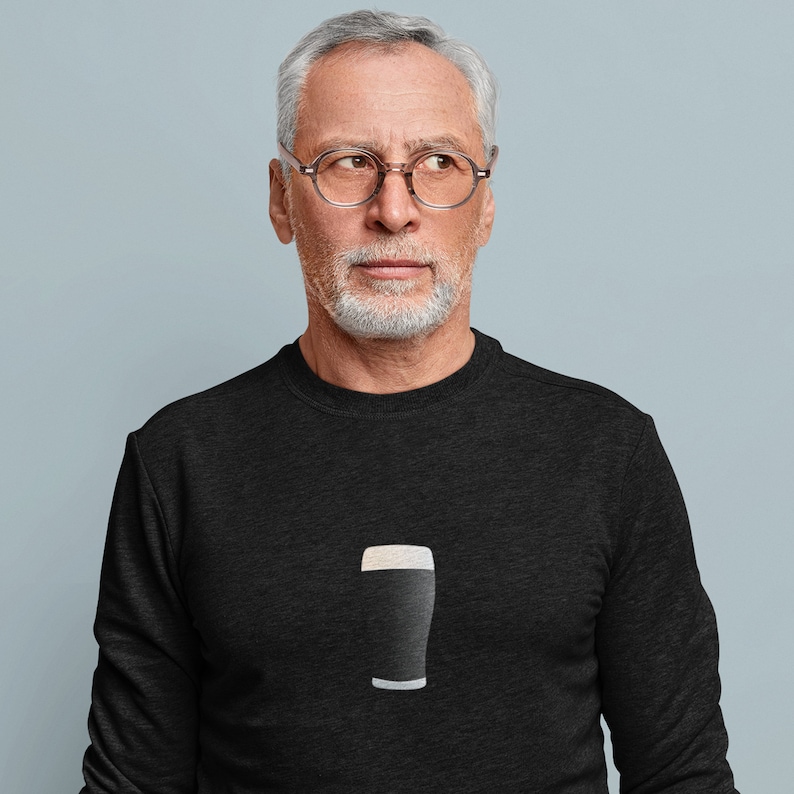 May include: Black sweatshirt featuring a graphic of a pint of stout. The design shows a dark beer with a creamy white head and a white base. The sweatshirt is a dark charcoal color.