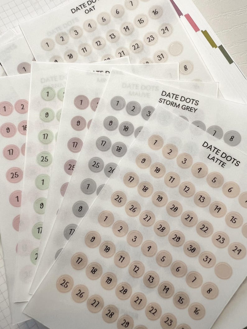 May include: Sheets of date dots in various colors, including oat, mauve, storm grey, and latte. Each dot is numbered from 1 to 31. The text "DATE DOTS" is printed at the top of each sheet.
