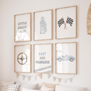 May include: A set of six framed art prints with a racing theme. The prints feature illustrations of a gas pump, checkered flags, a steering wheel, a vintage race car, and text that reads "Little Racer Dude" and "Fast and Fearless".