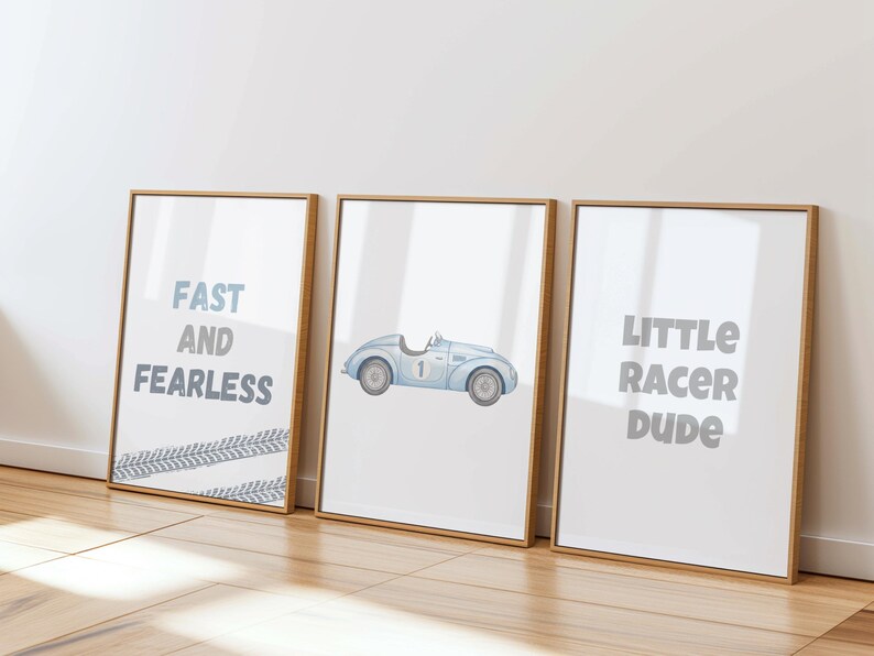 May include: Three framed art prints with a racing theme. One print reads "FAST AND FEARLESS" with tire track accents. The second print features a blue vintage race car. The third print says "LITTLE RACER DUDE". All prints have a white background.