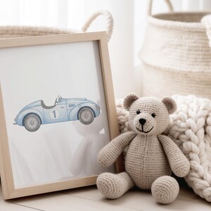 May include: A framed print featuring a light blue vintage race car with the number 1. A beige crocheted teddy bear sits next to the frame. Woven baskets and a cream-colored blanket are in the background.