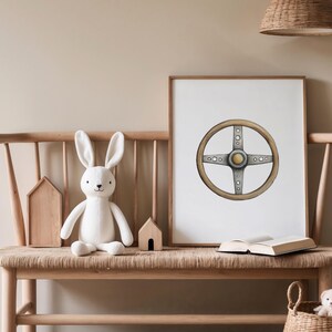 May include: A framed print of a vintage car steering wheel with a light wood grain and silver accents. The artwork is displayed on a wooden bench with a white stuffed bunny, wooden houses, and a woven basket.