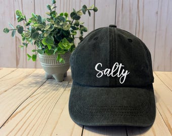 May include: A black baseball cap with a white embroidered word "Salty" on the front.
