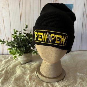 May include: Black beanie with a yellow and black embroidered patch that says "PEW PEW".