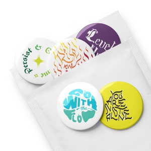 May include: Five round button pins with different designs and colors. The pins feature phrases like "Resist & Go", "Go With the Flow", "You Are Not Alone", "Rise Above the Flames", and "Level Up".