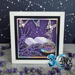 May include: A layered paper art piece in a white frame. The artwork features a purple night scene with butterflies, lavender, and a teacup. The teacup has steam rising from it. The background has a starry night sky.