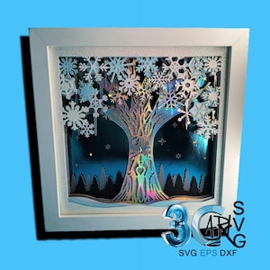 May include: A white frame containing a 3D paper cut-out design of a tree with snowflakes. The tree is iridescent and the background is a dark blue with stars.