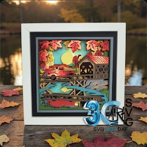 May include: A layered paper shadow box art piece in a white frame featuring a red truck driving across a wooden bridge near a covered bridge, surrounded by autumn maple leaves, a yellow sun, and a blue river, with 3D SVG DXF text in the corner.