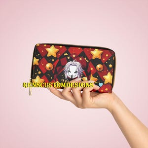 May include: A zip-around wallet featuring a red and black diamond pattern, gold stars, and a jester-like character illustration. The wallet has a gold zip and the text "RENSCUSTOMDESIGNS".
