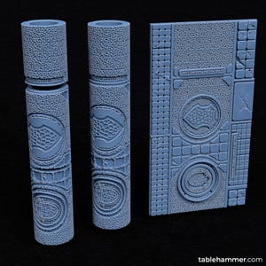 May include: Three 3D printed pieces for tabletop gaming. Two are cylindrical columns with a textured surface and a repeating pattern of a shield. The third piece is a flat textured surface with a repeating pattern of a shield and a square tile pattern. The pieces are a light blue colour.