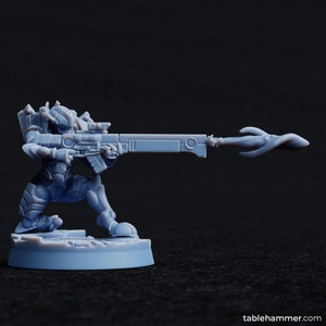 Könnte beinhalten: Eine graue Plastikminiatur eines futuristischen Soldaten, der kniet und mit einem Gewehr mit glühender Spitze zielt. Der Soldat trägt eine Rüstung und einen Helm mit Visier. Die Miniatur steht auf einem grauen Sockel.