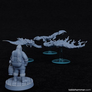 Könnte beinhalten: Vier graue Plastik-Miniaturfiguren von skorpionartigen Kreaturen mit Flügeln und Schwänzen. Die Figuren stehen auf durchsichtigen Plastiksockeln. Eine graue Plastik-Miniaturfigur einer Person, die einen Mantel trägt und einen Eimer hält, befindet sich im Vordergrund.