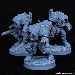 May include: Three gray plastic miniature figures of robots wearing armor and helmets. The robots are standing on circular bases with a textured surface.