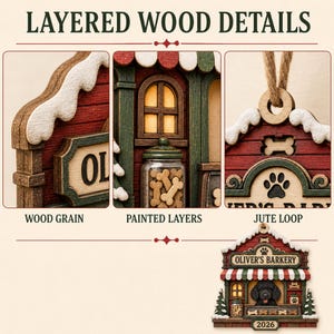 May include: A layered wood ornament shaped like a shop titled OLIVER'S BARKERY, featuring a black dog, a jar of bone treats, a red and white striped awning, snow-dusted roof, and a jute hanging loop. The text 2026 is printed at the bottom.