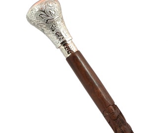 May include: A wooden walking stick with a silver-colored, ornate handle. The stick has intricate carvings throughout the shaft.