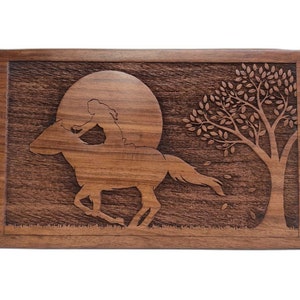 May include: A wooden box with a carved design of a woman riding a horse under a full moon with a tree in the background.