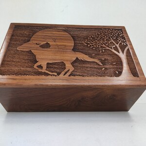 May include: A wooden box with a carved design of a horse and rider galloping under a full moon with a tree in the background.