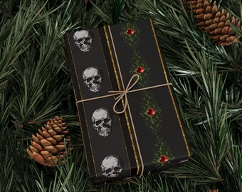 May include: Black gift wrap featuring white skull designs and gold stripes. The wrap is tied with twine and has a decorative pattern with red accents. The background includes pine needles and pine cones.