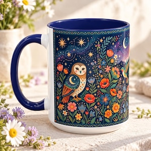 May include: A white ceramic mug with a deep blue interior and handle, featuring a vibrant illustration of a brown owl perched among colourful flowers, green foliage, and a starry night sky with a crescent moon on the exterior surface.