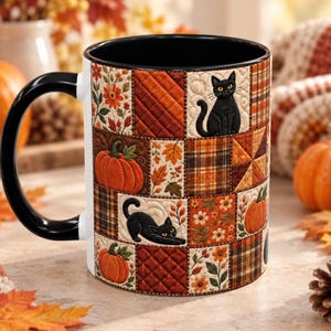 Puede incluir: Una taza de cerámica con asa e interior negros, que presenta un diseño de colcha de retazos. El patrón incluye gatos negros, calabazas naranjas, hojas de otoño, motivos florales y cuadrados a cuadros en tonos naranja, marrón y crema.