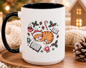 May include: A white ceramic mug with a black handle and interior rim, featuring a graphic of an orange tabby cat wearing a Santa hat, surrounded by illustrations of books, holly, acorns, a candy cane, a mug of cocoa, and winter mittens.