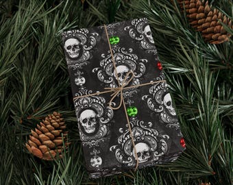 May include: A wrapped gift with black wrapping paper featuring a white skull and ornate design. The gift is tied with twine and decorated with green and red accents. The background includes pine needles and pine cones.