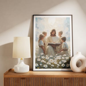 Puede incluir: Una pintura de Jes&uacute;s leyendo un libro a cuatro ni&ntilde;os en un campo de flores blancas. Los ni&ntilde;os visten ropa blanca y azul. La pintura est&aacute; enmarcada en un marco negro.