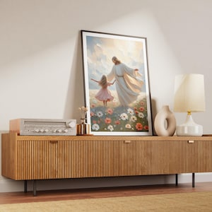 May include: A framed painting depicting a man in a white robe holding a young girl's hand as they walk through a field of flowers. The painting is displayed on a wooden cabinet with a stereo system and a lamp.