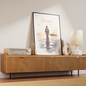 May include: A framed watercolor painting of a person walking on water with a boat in the distance. The painting is hanging on a wall above a wooden cabinet with a stereo and a lamp.