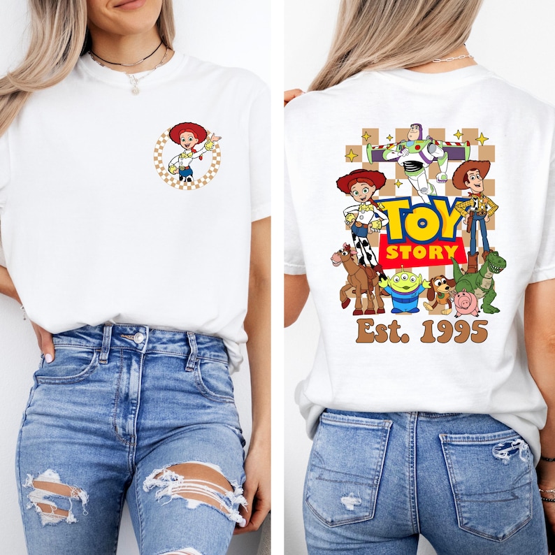 May include: White t-shirt featuring a front and back graphic design. The front displays a cartoon of a cowgirl in a circle. The back features the words "TOY STORY" with characters and "Est. 1995".